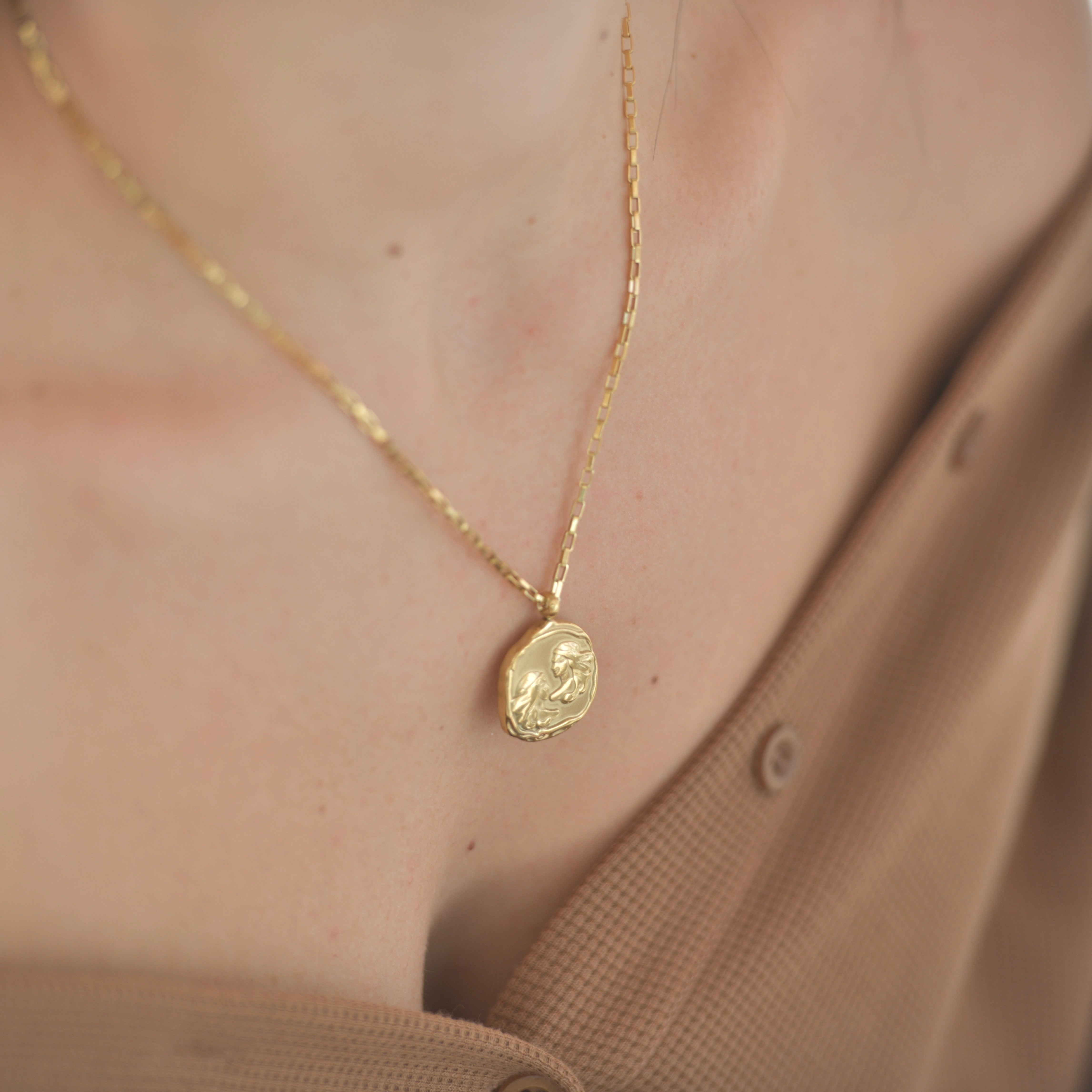 Gemini Zodiac Medallion Gold Necklace - Gold plated medallion irregular shape with two people rpresentin the twins - geminis on it. Gold chain necklace.