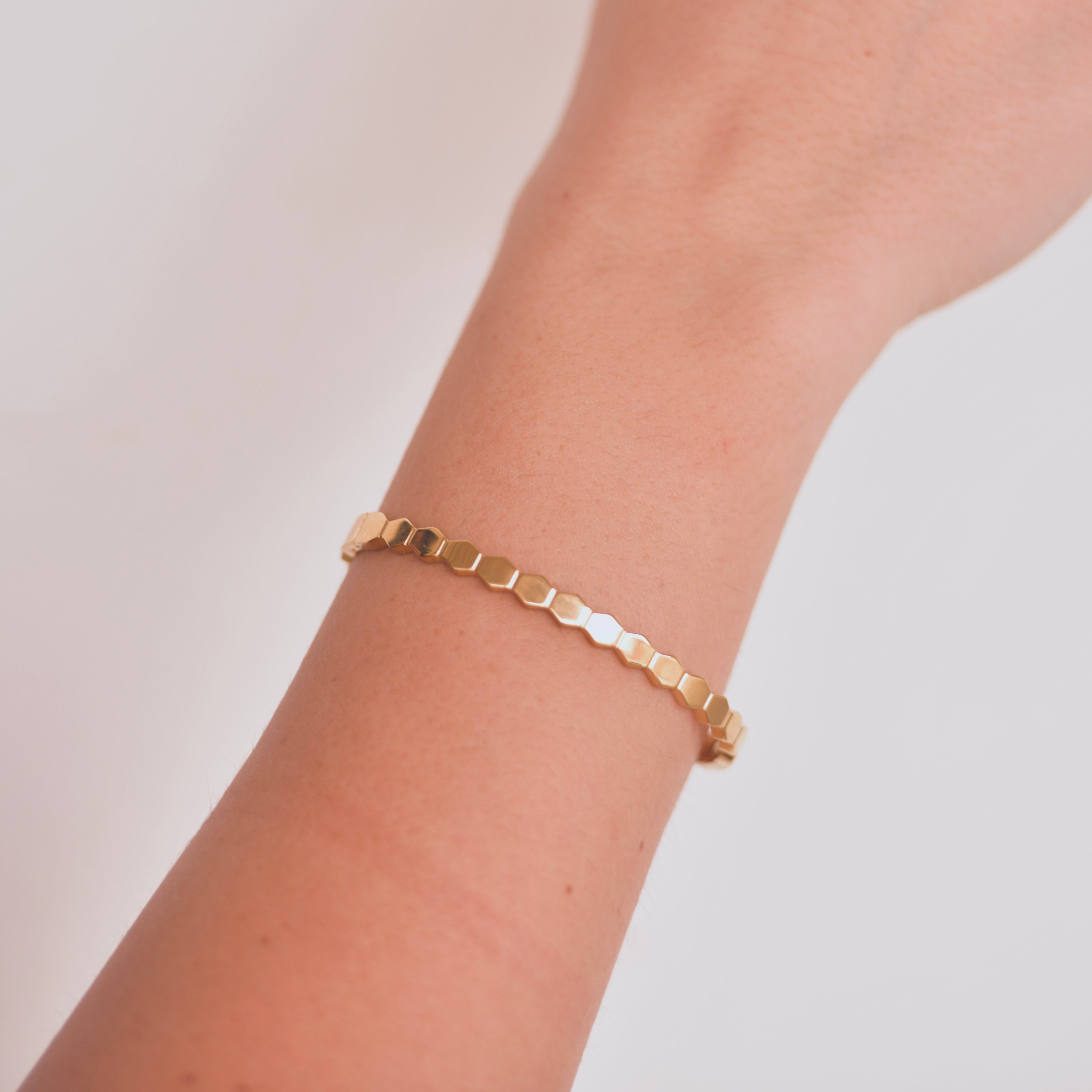 Gold bracelet with the design of bee hives attached with one another creating a circle,