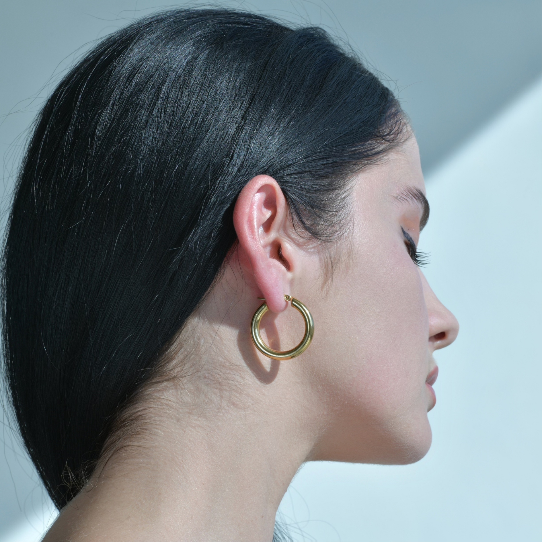 Woman model wearing Gold plated hoops. Round circle earrings plated in gold.