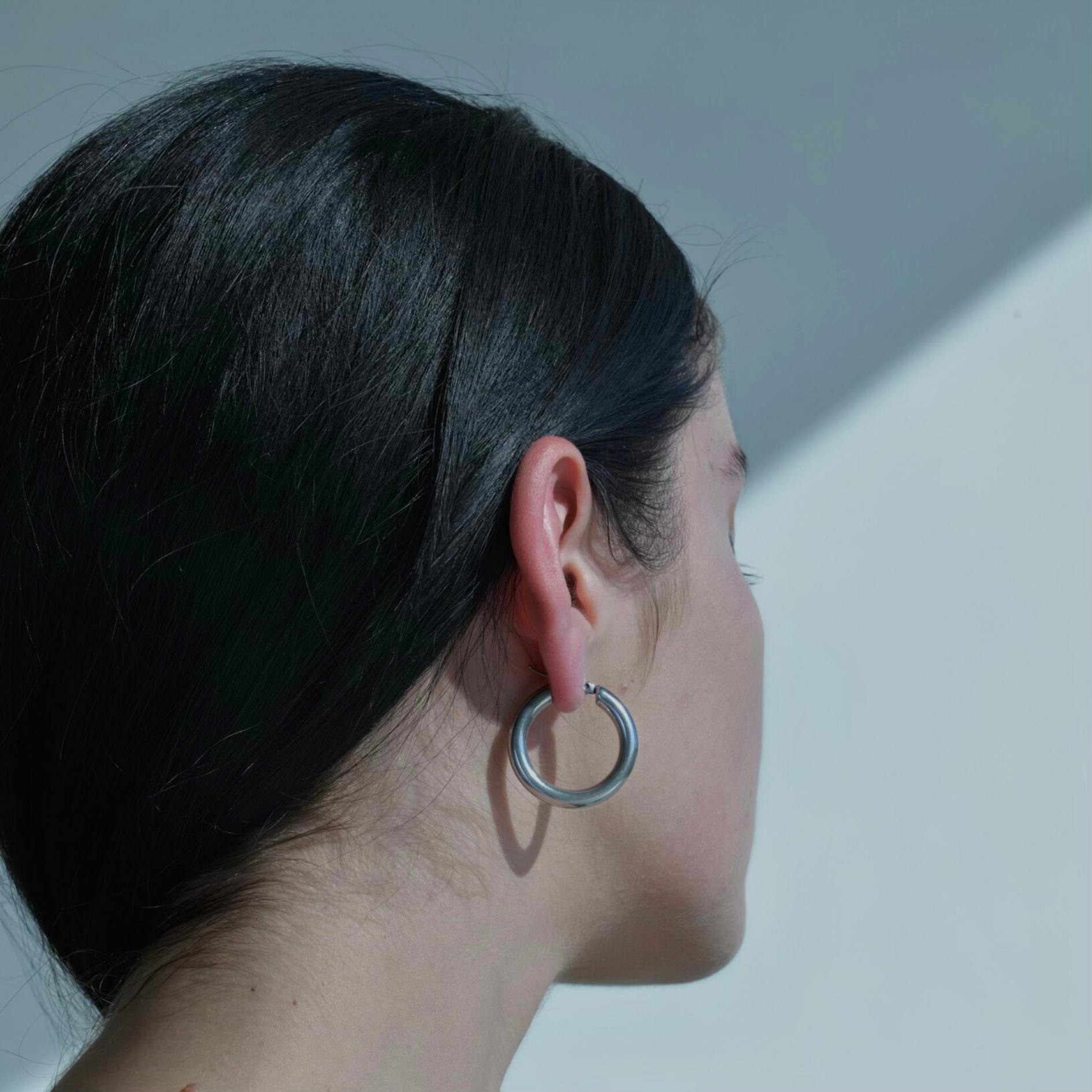 woman model wearing in her ear Classic silver plated hoop earrings Round circle earrings with a silver plating.
