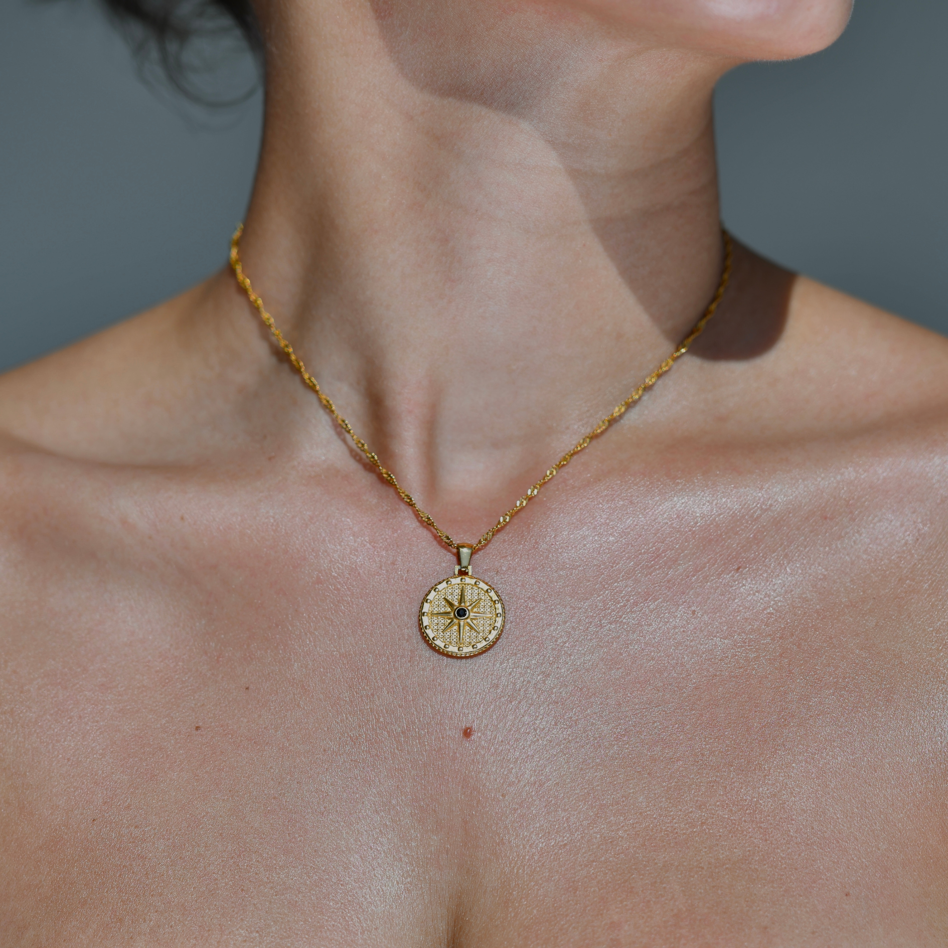 Circle Round waterproof pendant. Compass gold pendnat. Gold chain. The pandant is droped on the chain. A black zircon is in the moddle of the pendant. Compass Pendant Gold Necklace.