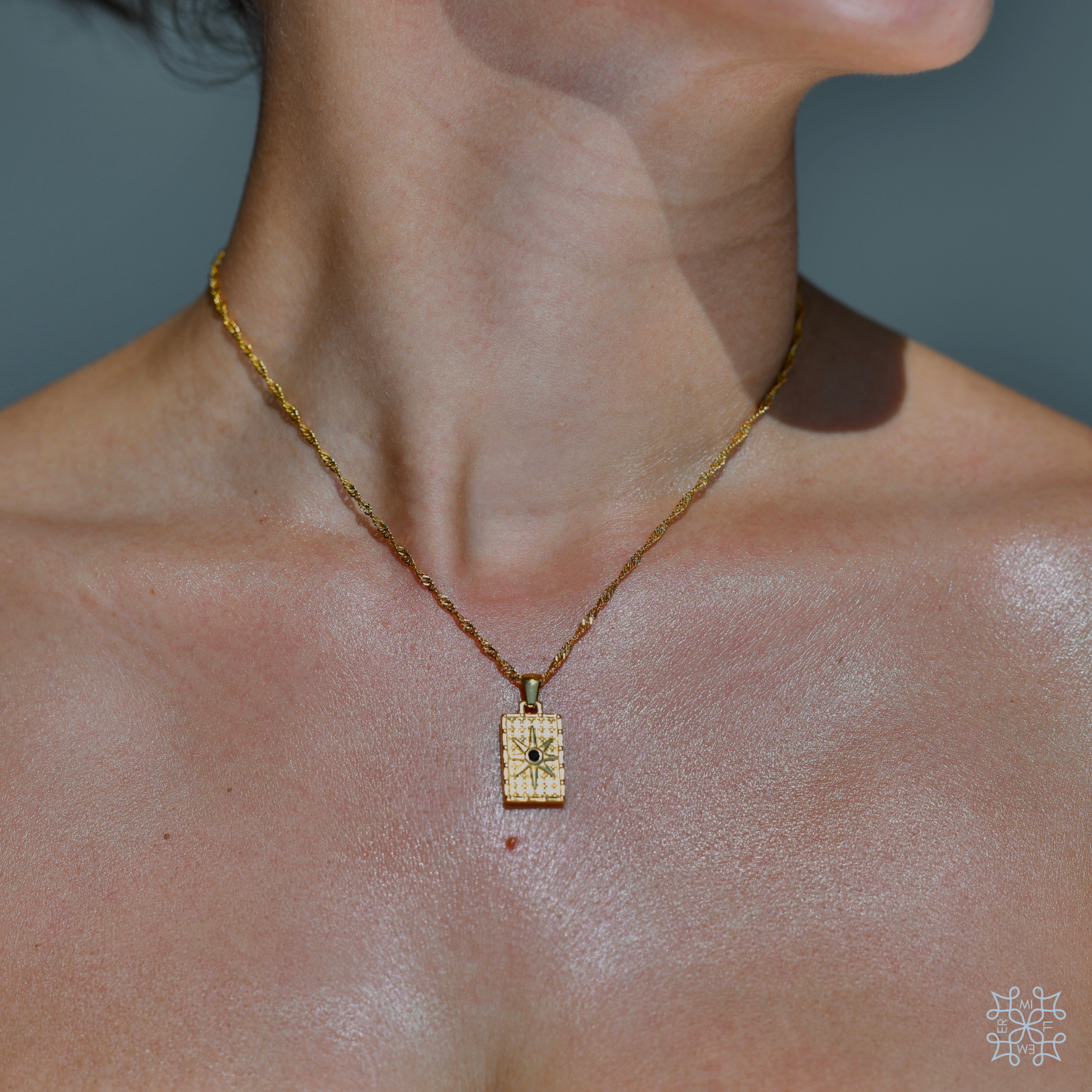 Rectangular compass Gold pendant. A star engraved in the top of the pendant with a black zircon in the middle. th ependant has the same design in both sides of ot. It has a long gold chain. 