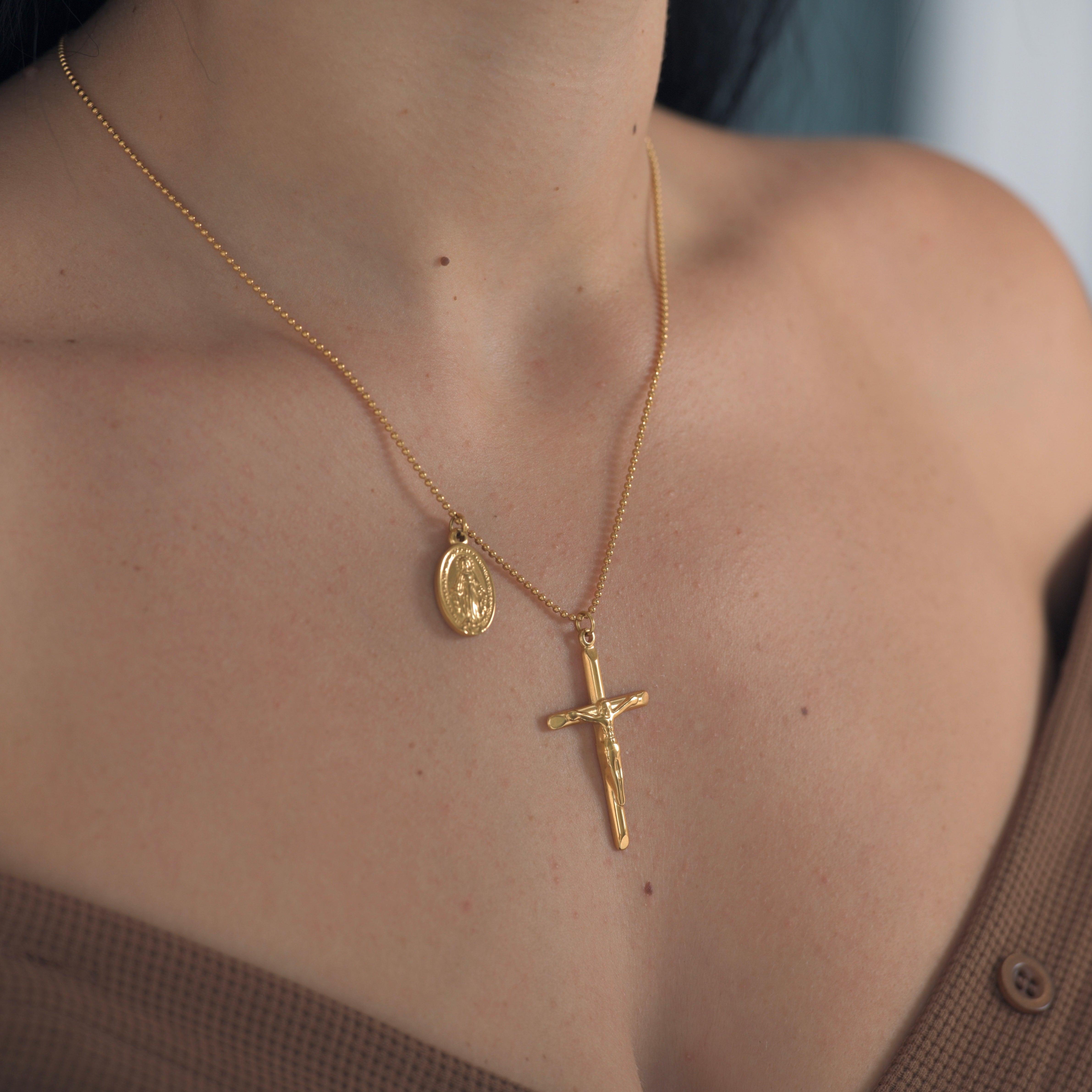 Gold cross pendant necklace. Cross pendant with jesus crist in the crucifix. Oval shape small drop on the side with mother mary on top of it.