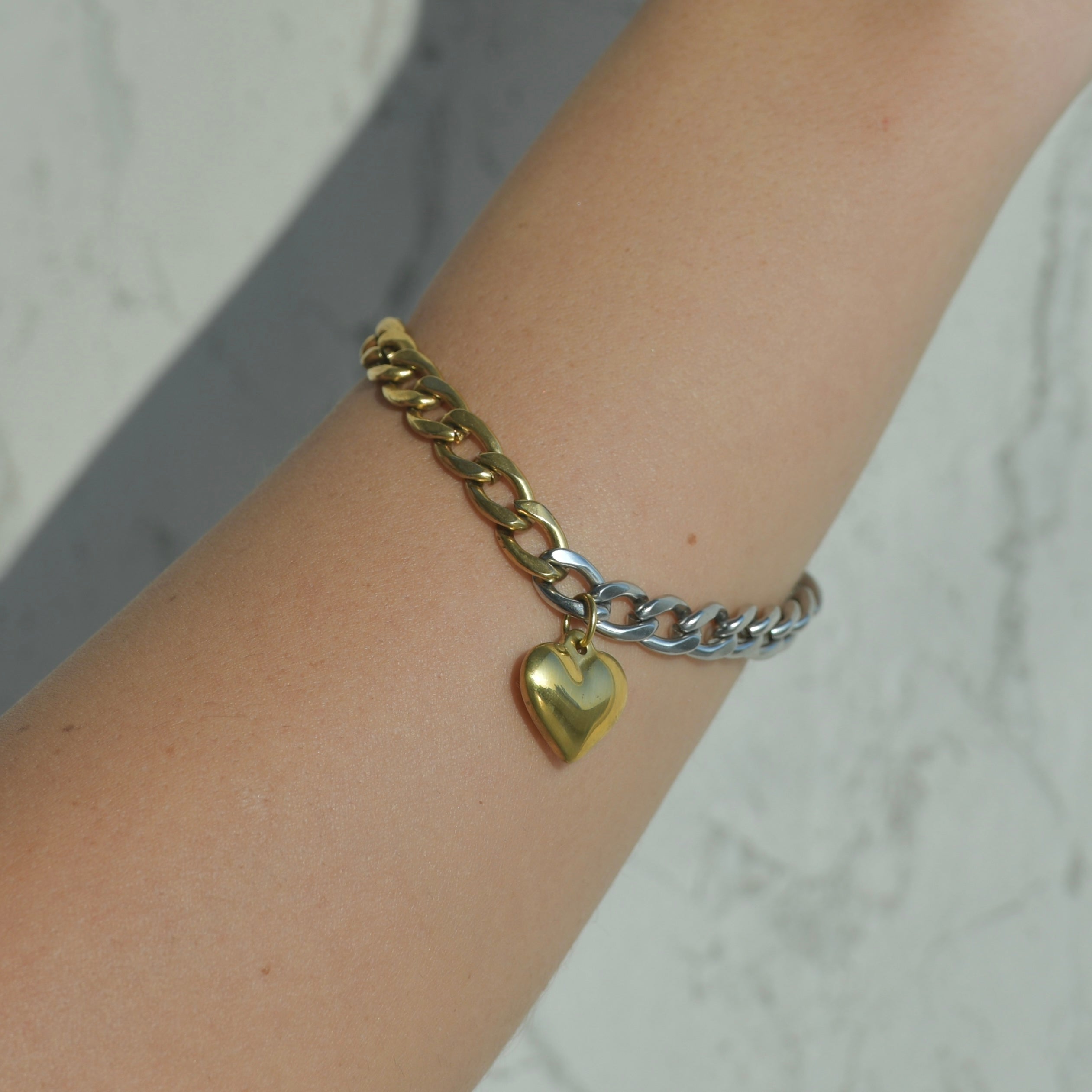 Cuban chain bracelet. Half gold and half silver with a gold heart pendant in the middle of the bracelet.