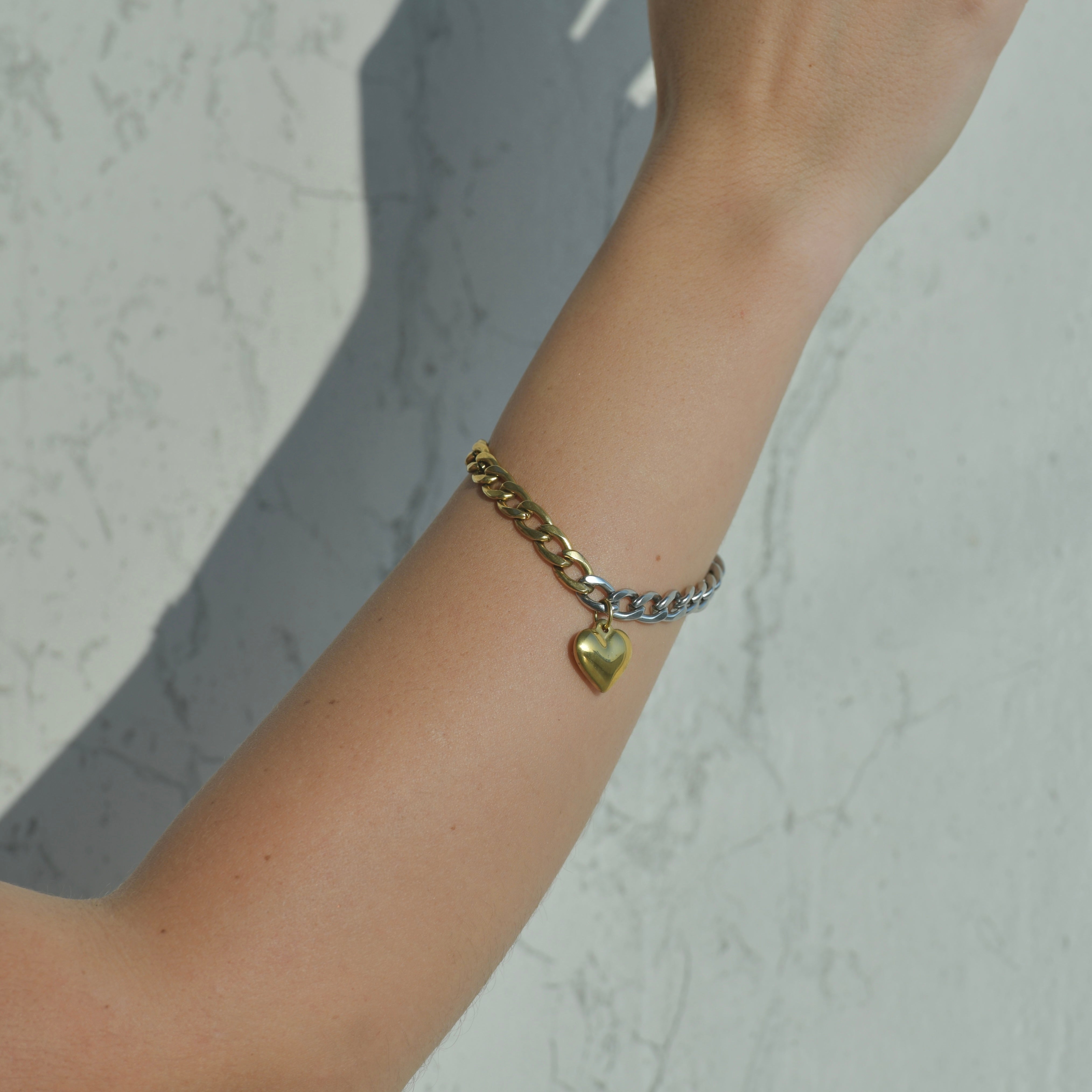 Cuban chain bracelet. Half gold and half silver with a gold heart pendant in the middle of the bracelet.