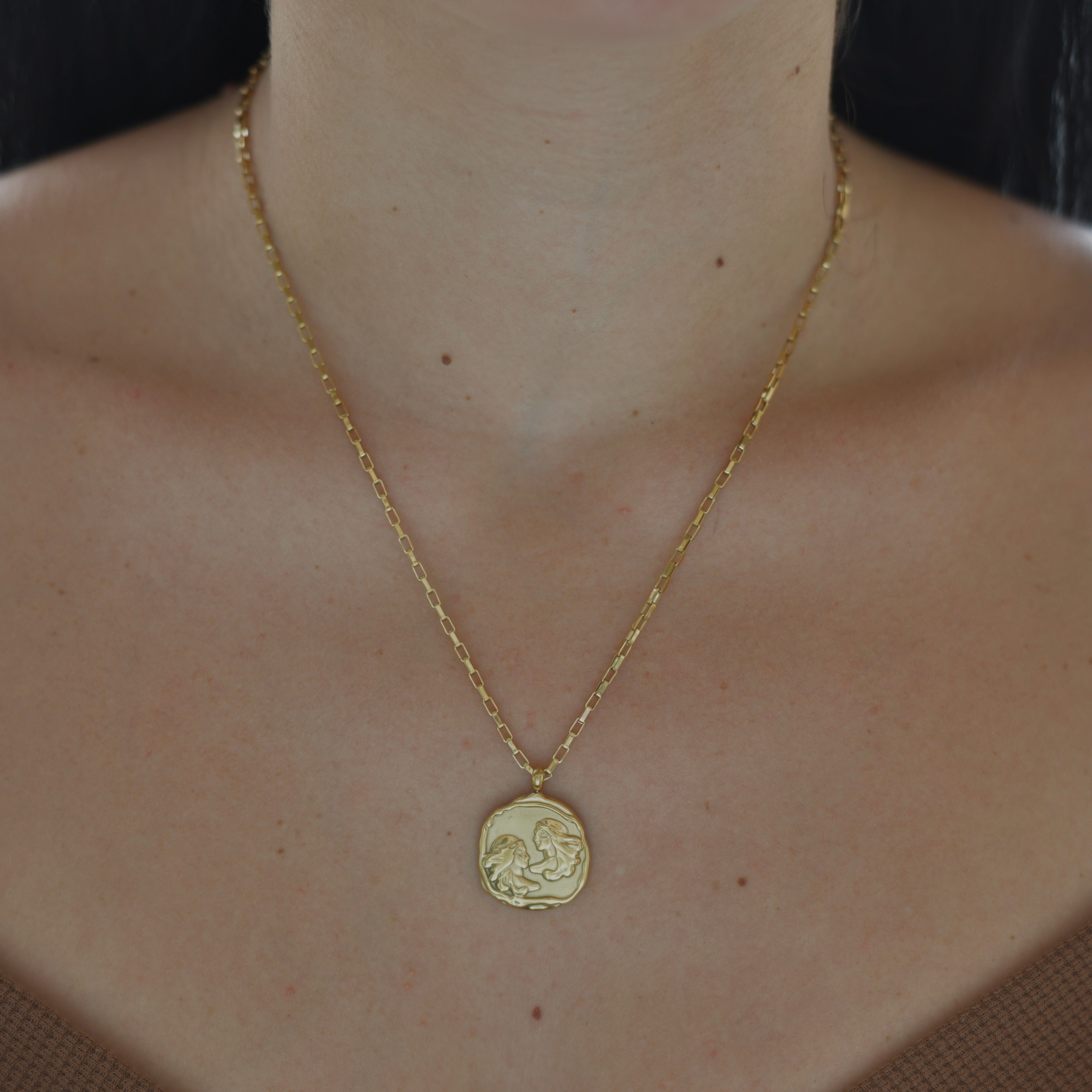 Gemini Zodiac Medallion Gold Necklace - Gold plated medallion irregular shape with two people rpresentin the twins - geminis on it. Gold chain necklace.