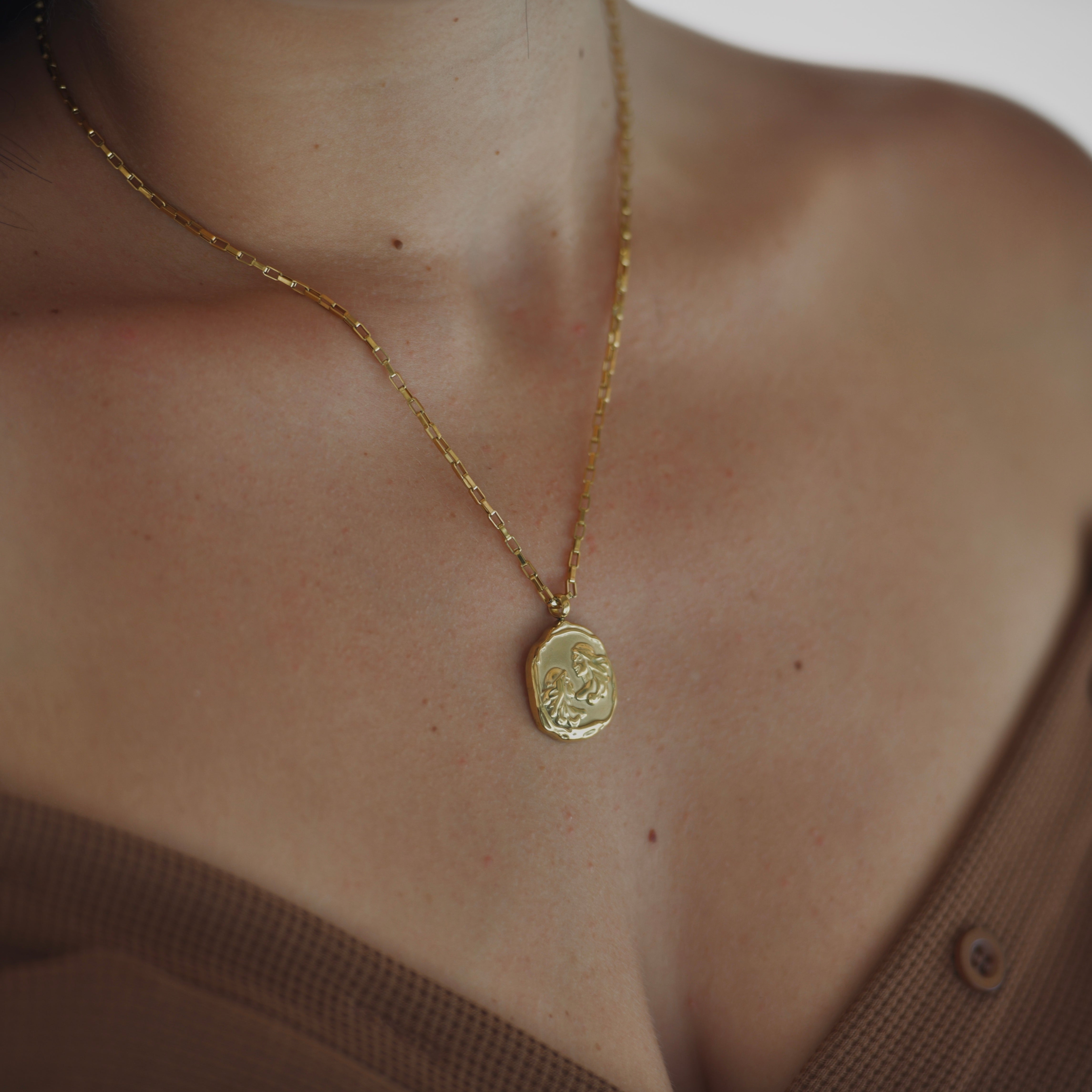 Gemini Zodiac Medallion Gold Necklace - Gold plated medallion irregular shape with two people rpresentin the twins - geminis on it. Gold chain necklace.