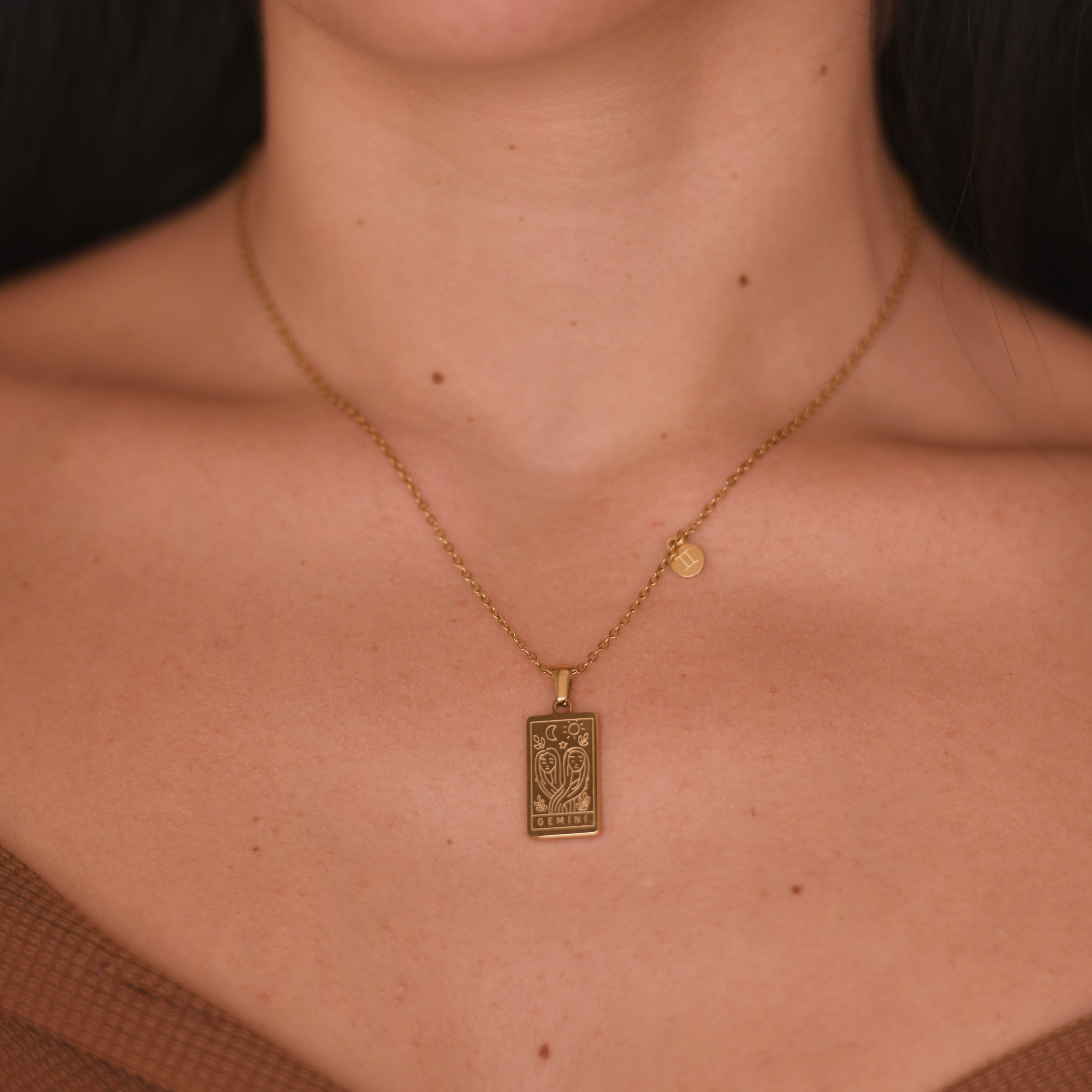 GEMINI Zodiac Pendant Gold Necklace - Gold chain necklace with gemini engraved in a vertical rectangular shape pendant. at the bottom of the pendant is engraved the word "gemini". on the side of the pendant at the chain is attched a square charm with gemini symbol engraved on it.
