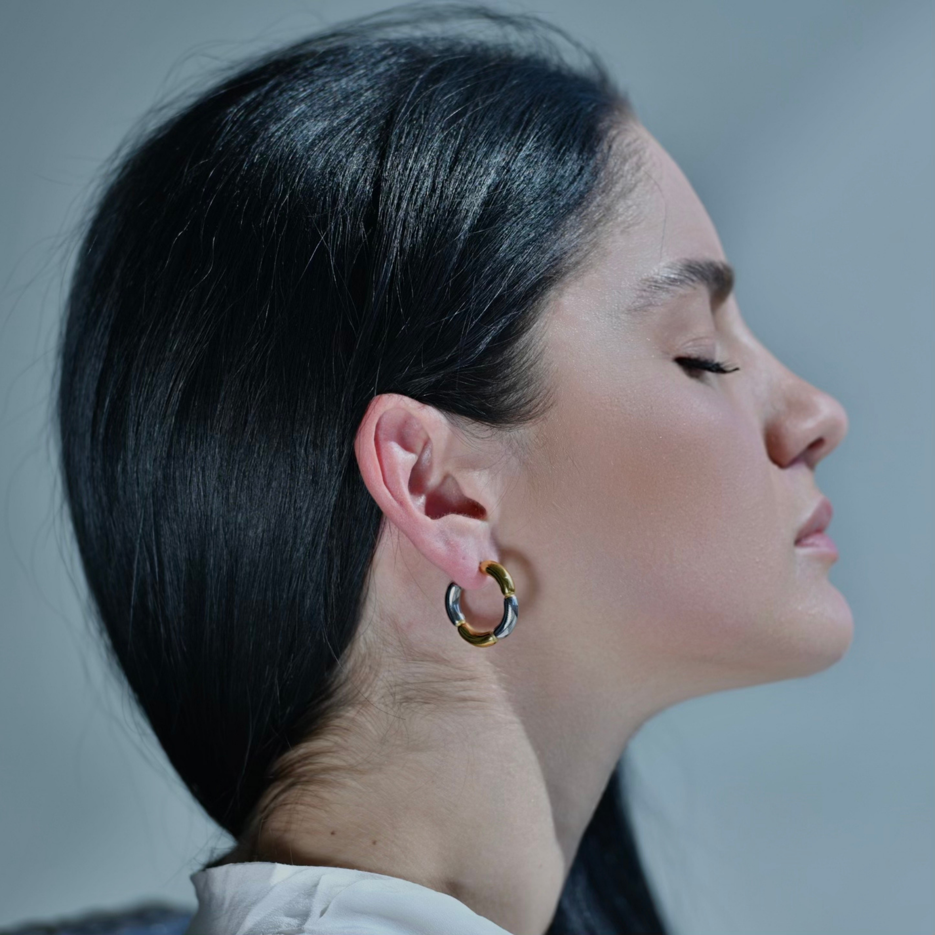 Woman wearing in the ear. Gold and Silver Hoop earrings divided on chunky segments plated in gold and silver creating a flower shape.