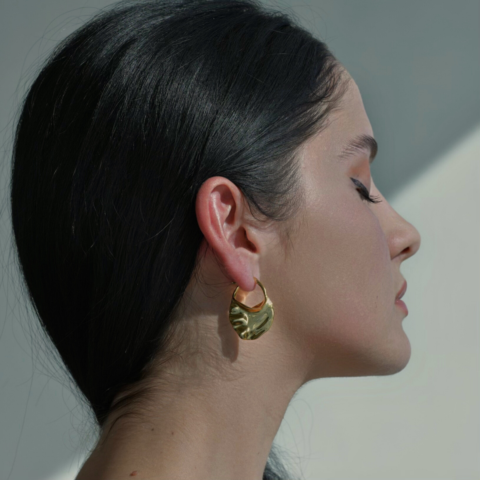 Gold earrings in the irregular oval shape.