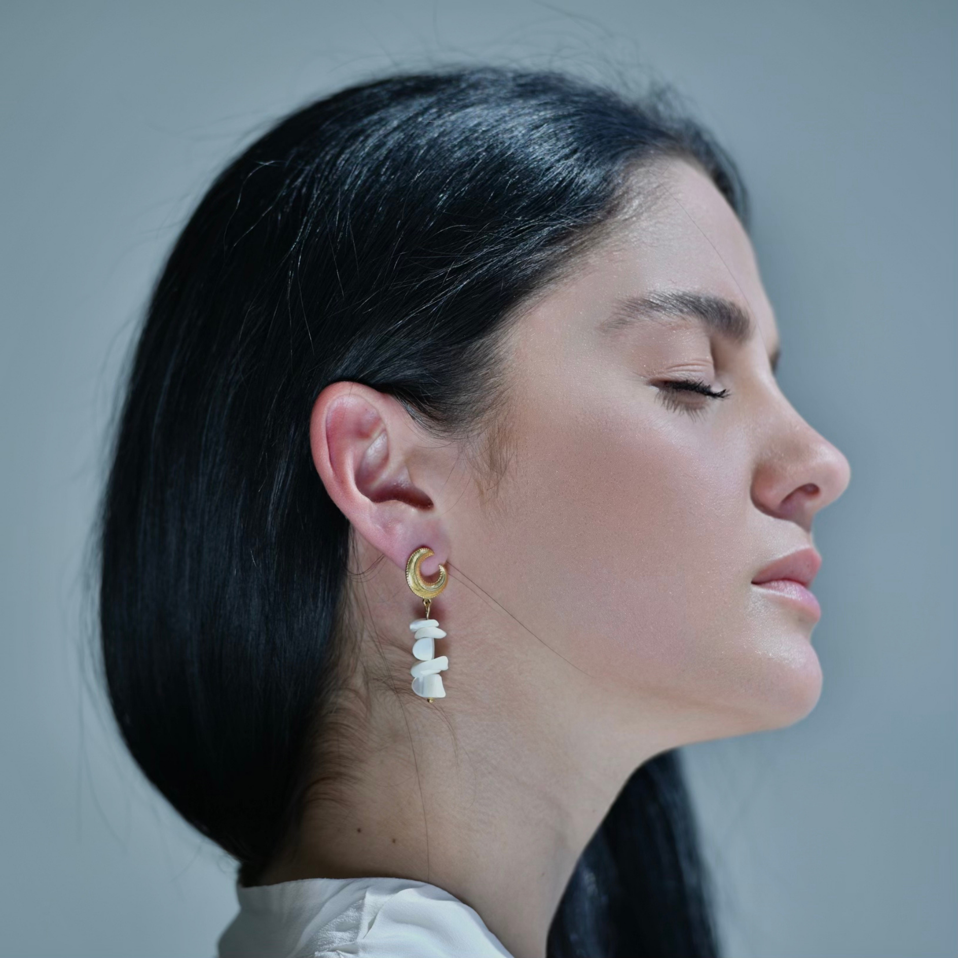 LUNAR Irregular white pieces attached one with another forming a drop earring. At the top is a gold half draped moon shaped gold piece.