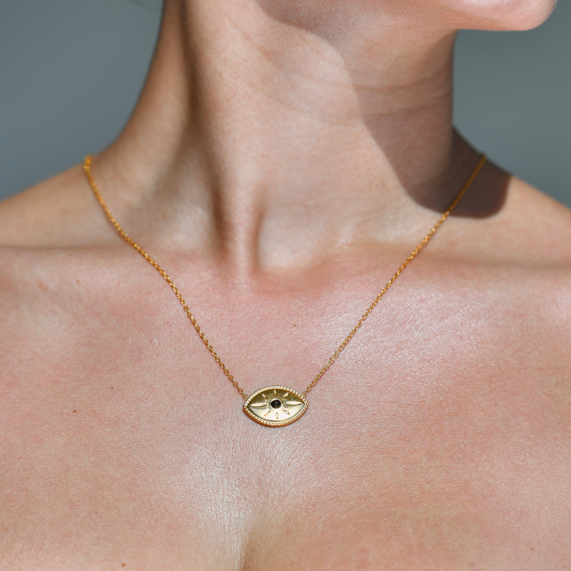 horizontal gold pendant. Eye shaped pendant with a black onyx stone in the middle of it. Chained both sides of the eye with the chain. Onyx Eye Gold Necklace