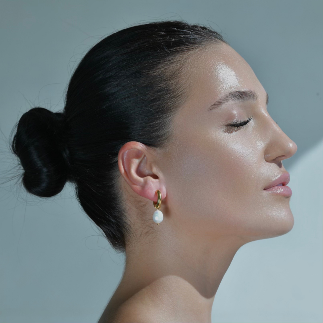 Women model wearing GOLD plated pearl earrings. round gold hoops with detachable pearl drop.
