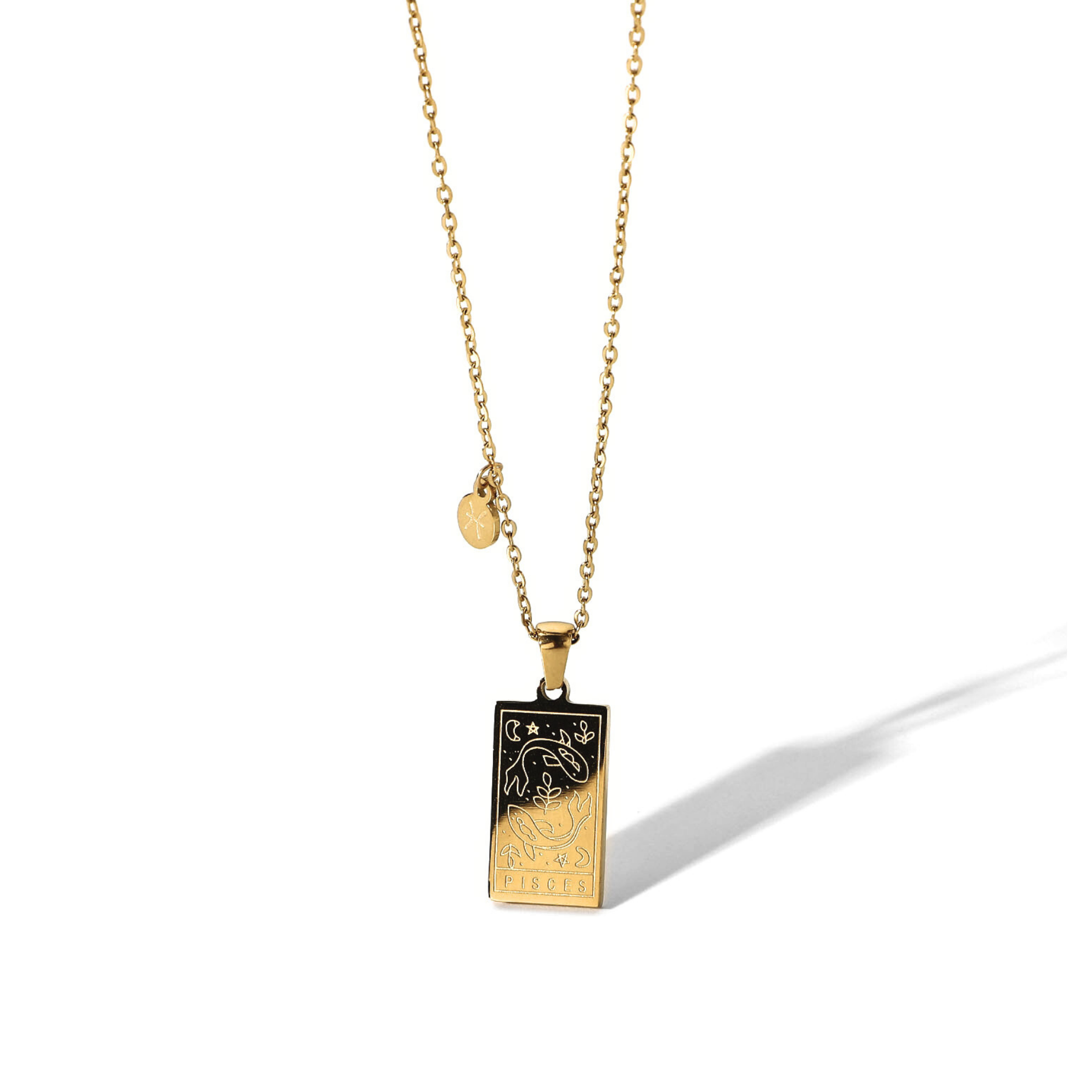 Rectangular gold pendant with two fish engraved and the word pisces in the bottom. Gold pendant with a chain necklace. In the side of the gold pendant is a circle small medalion with the symbol of pisces engraved on it. Pisces zodiac pendant gold necklace.
