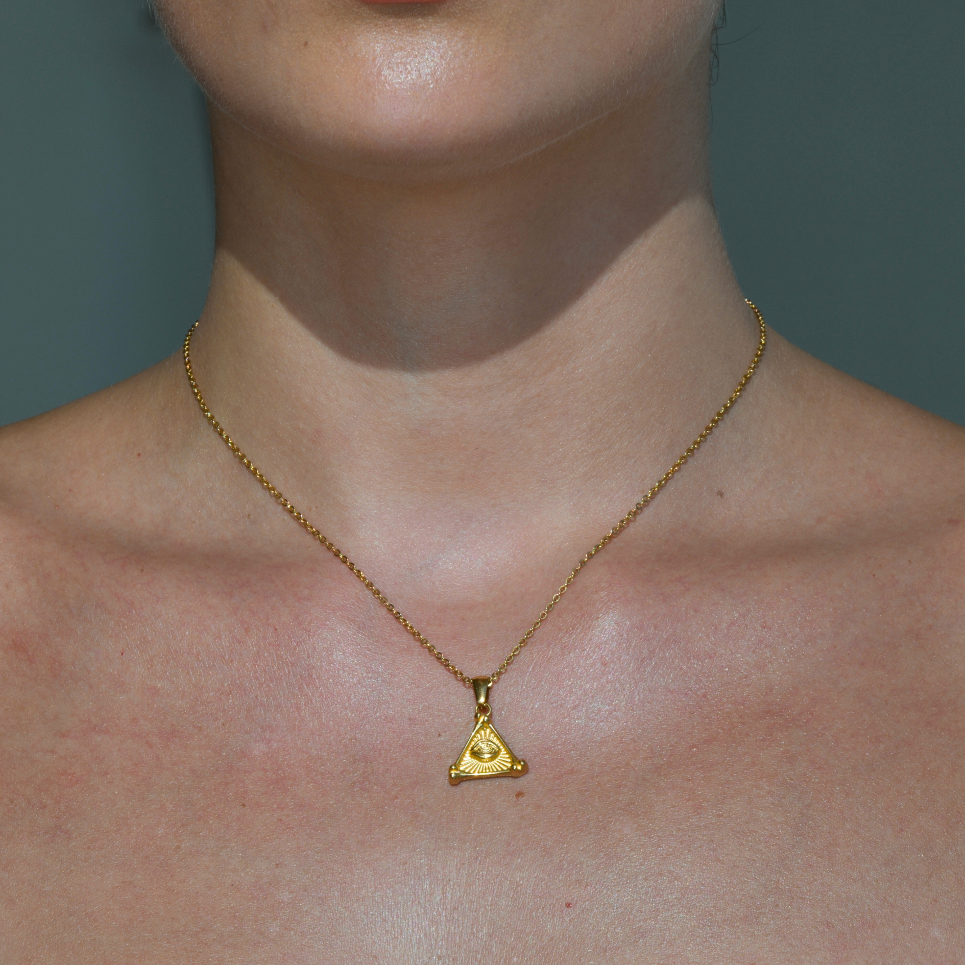 Gold Necklace. the pendant has the shape of a pyramid with an eye in the middle of the rays inside the pyramid surface. Pyramid Pendant Gold Necklace.