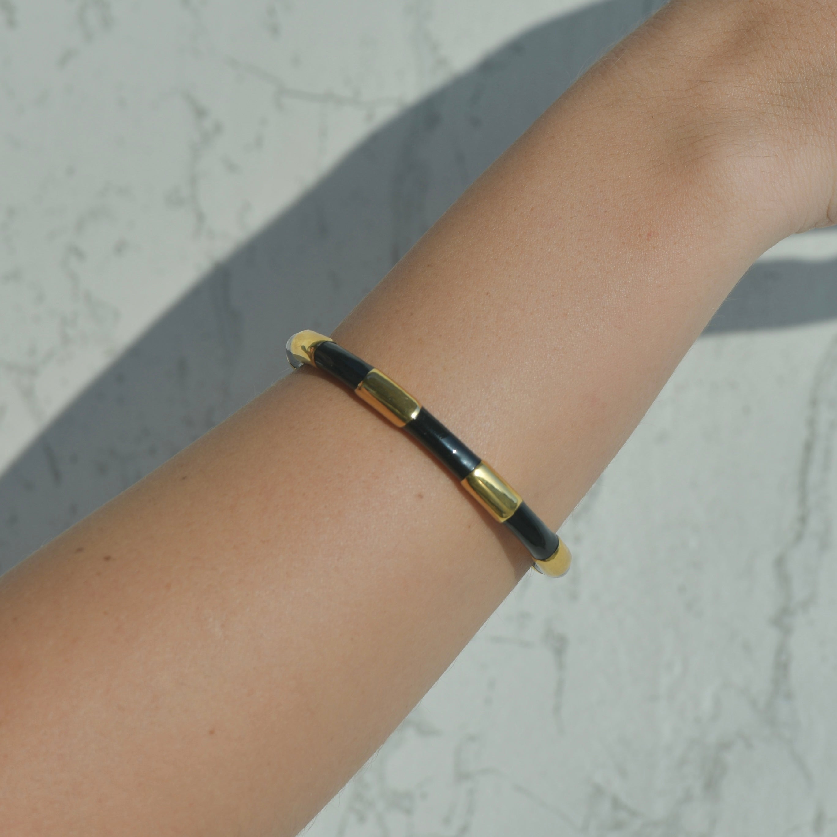 Gold Cuff bracelet. Black enamel painted creating the idea of a black ribbon around the gold cuff.