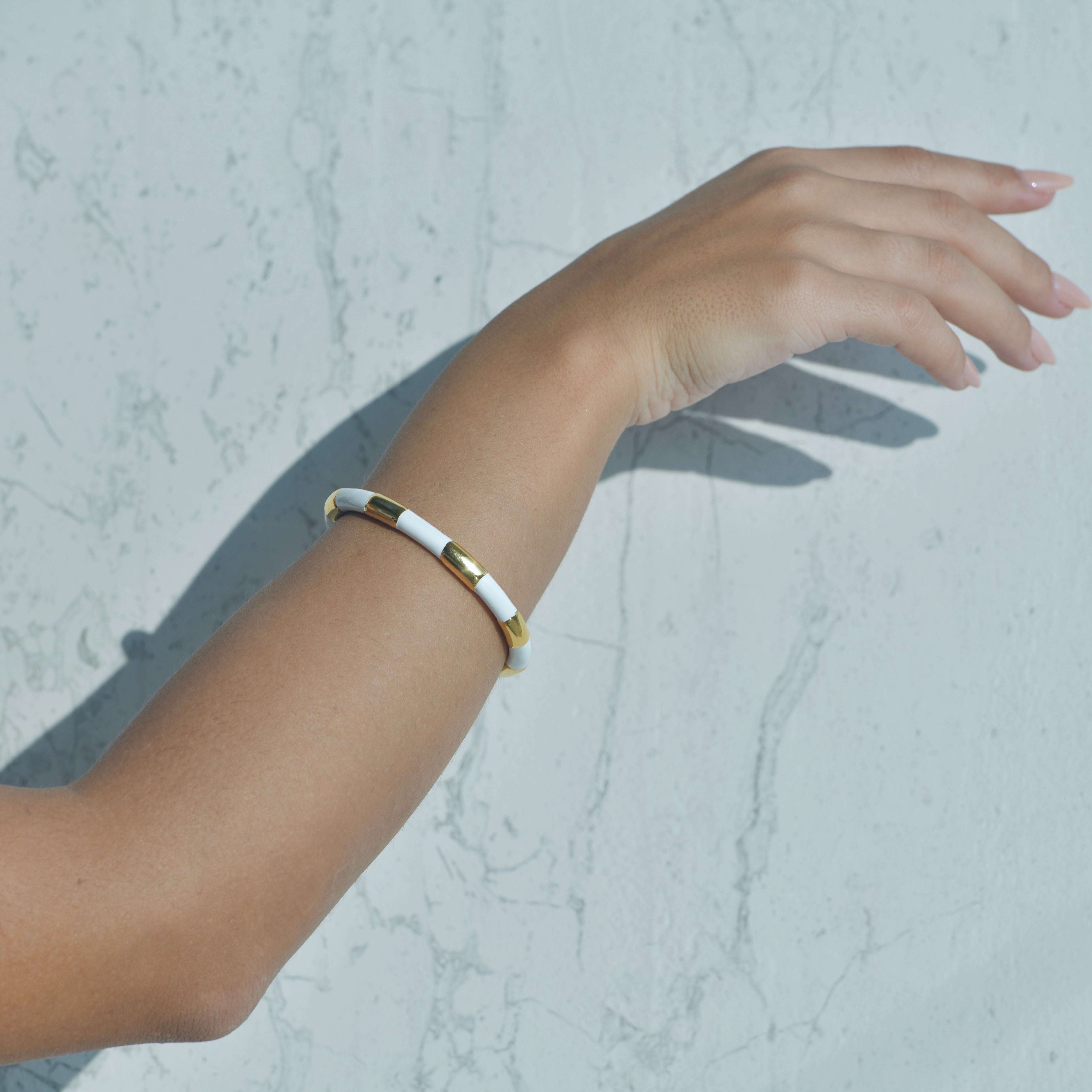 Gold Cuff bracelet. White enamel painted creating the idea of a white ribbon around the gold cuff.
