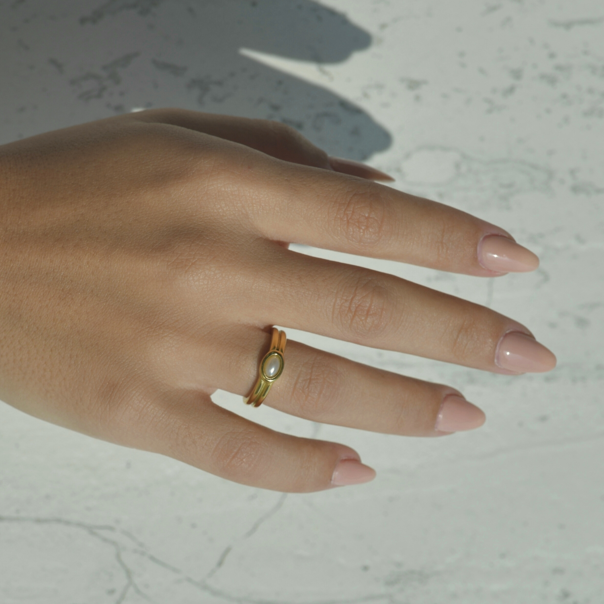 Santorini Pearl Gold Halo Ring. Gold ring with an oval horizontal shape in the middle of the ring.