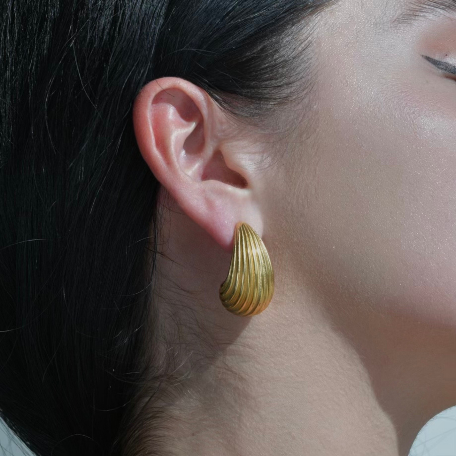 Gold pebble Earrings with lines engraved in the metal. The earrings have the form of a waterdrop.