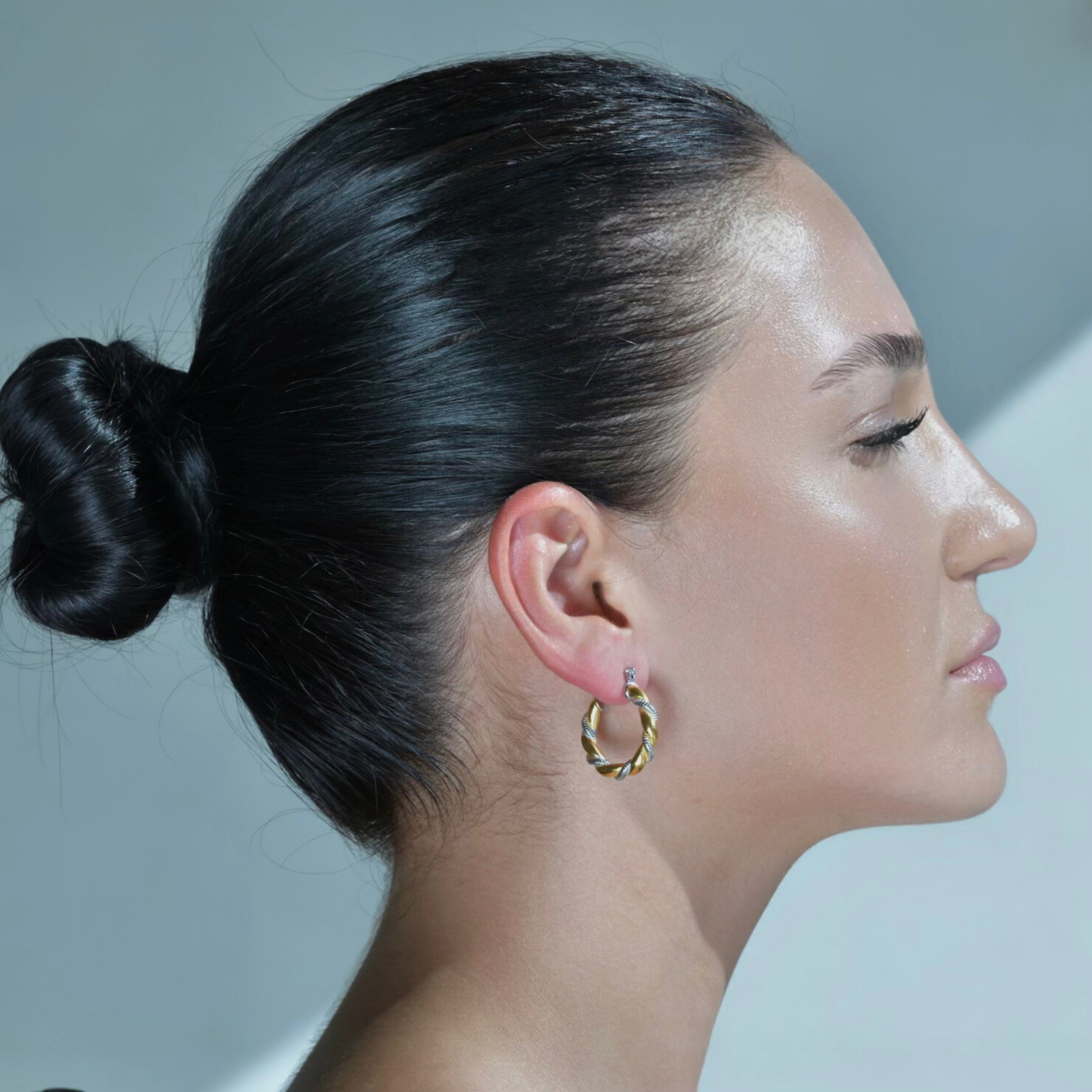 Model wearing Gold hoop earrings with twisted silver elegant nail  twisted around it. A mixed metal hoop.