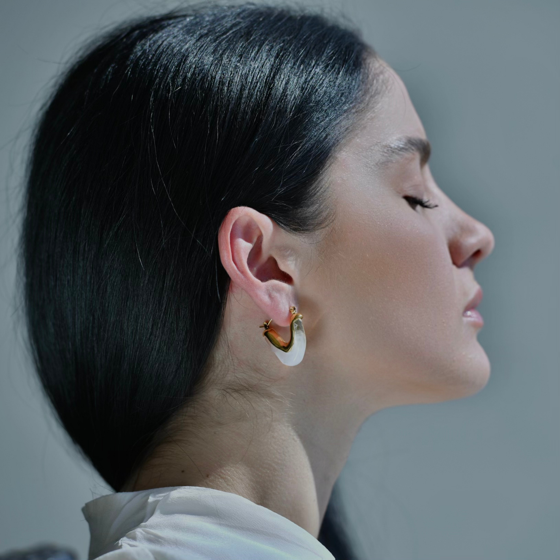 Model wearing, V shape earring in gold plated  metalic with white Acrylic. 