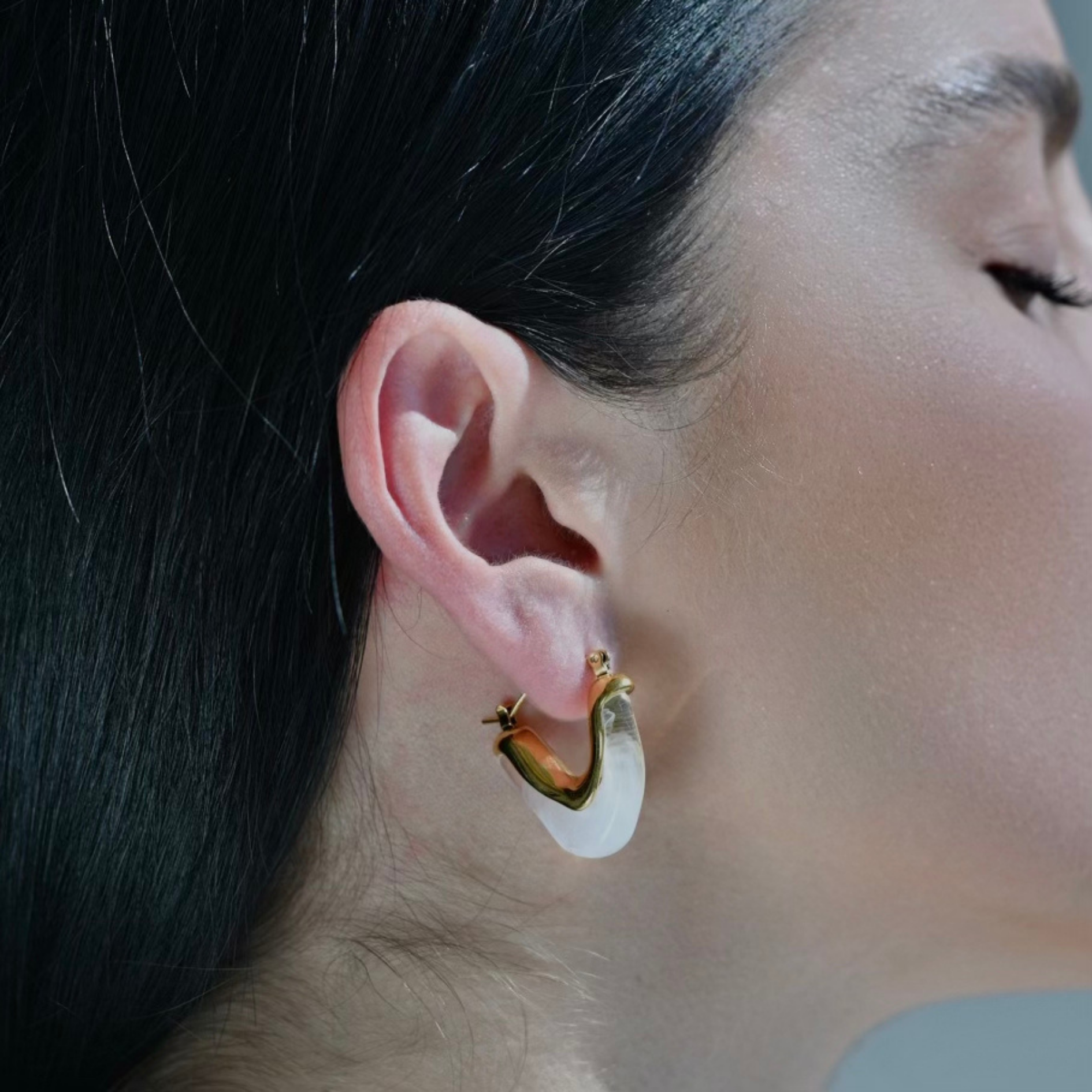 Model wearing, V shape earring in gold plated metalic with white Acrylic.